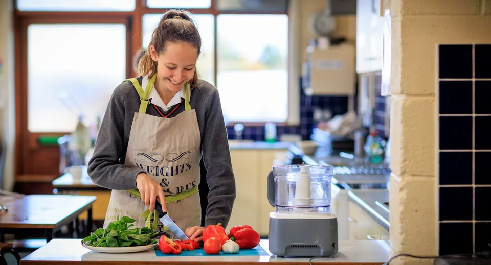 Una studentessa del Kilkenny College prepara verdure fresche nella cucina della scuola.