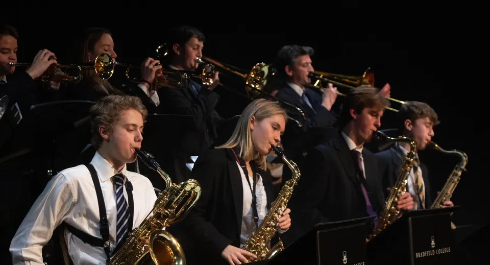 Un gruppo di musicisti suona ottoni e legni sul palco del Bradfield College.