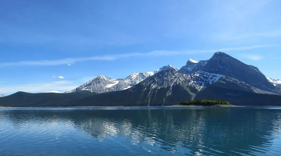 Paesaggio montano con cime innevate e un lago limpido come uno specchio in primo piano vicino alla National Sport School.