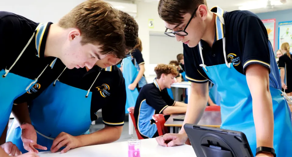 Studenti della Ormeau Woods State High School lavorano insieme a un'attività di gruppo attorno a un tavolo.