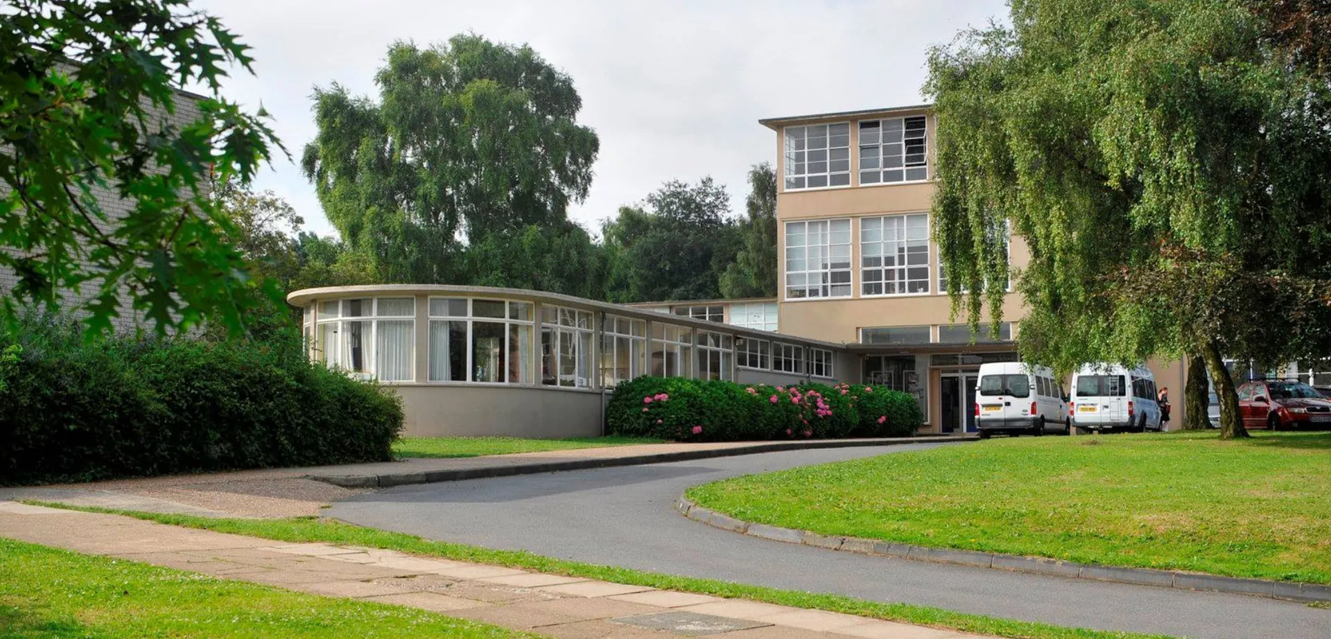 L'edificio moderno a più piani con facciata in vetro curvato della Highworth Grammar School è circondato da un paesaggio verde.