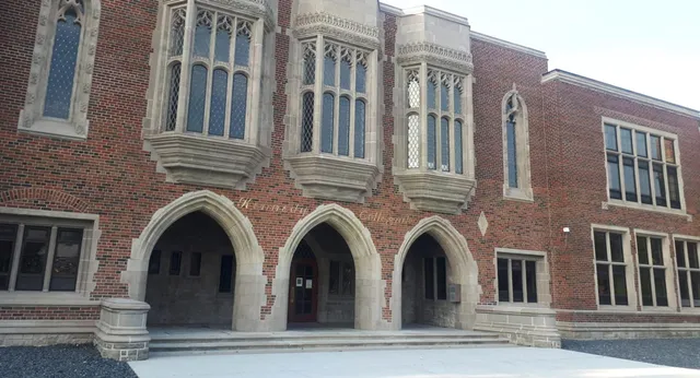 Das Gebäude der Honourable W.C. Kennedy Collegiate zeigt gotische Architektur mit verzierten Steinmetzarbeiten und einem Treppenaufgang am Eingang.