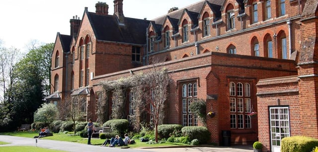 Alcuni studenti siedono sul prato davanti all'edificio in mattoni rossi dell'Oxford International College.