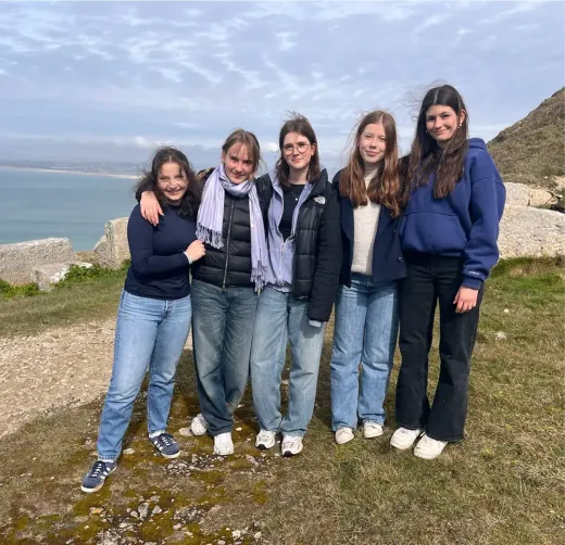 Fünf Mädchen Arm in Arm auf einer Klippe mit Blick aufs Meer in England