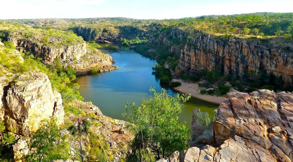 Un lago tranquillo con ripide scogliere e un paesaggio verde sotto un cielo blu, circondato dalla natura vicino al Yanchep Secondary College.