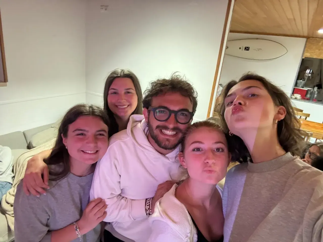 Selfie di gruppo di cinque giovani sorridenti al chiuso