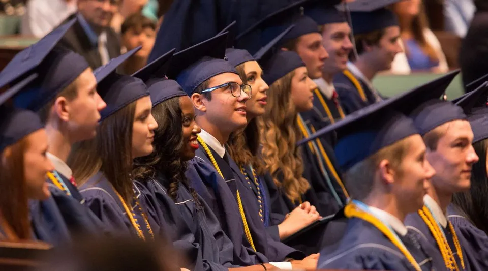 Un gruppo di diplomati e diplomate della Providence Christian Academy si trova insieme in abito accademico durante una cerimonia solenne.
