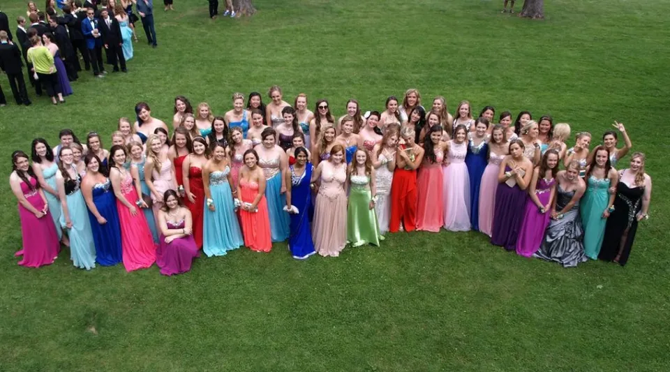 Un grande gruppo di studentesse del Brockville Collegiate Institute in abiti colorati si trova su un prato.