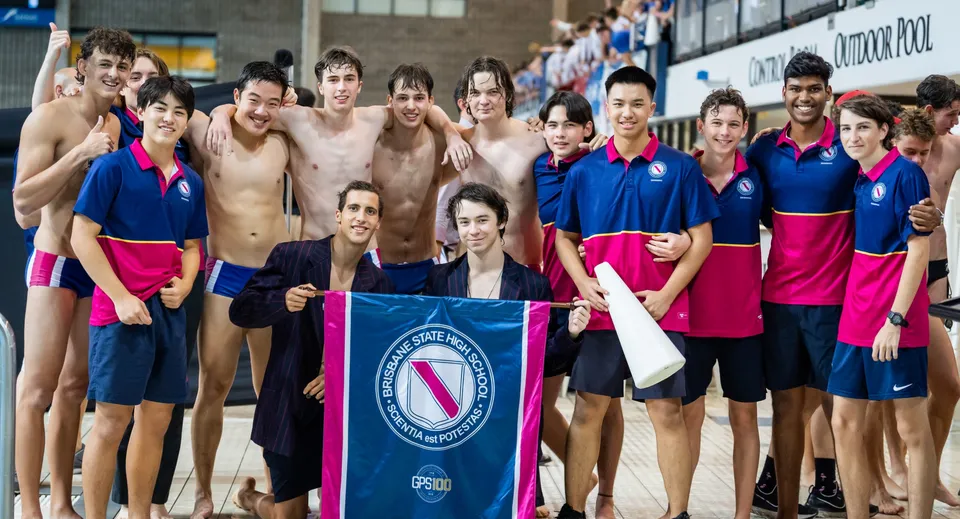 Un gruppo di nuotatrici e nuotatori posa davanti al banner della Fédération Internationale de Natation nel campus della Brisbane State High School.
