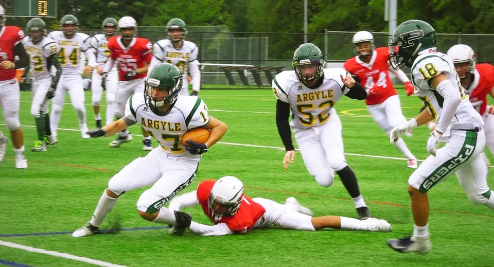 Gli studenti della Argyle Secondary School giocano una partita di football e mettono a segno un tackle sul campo durante la partita.