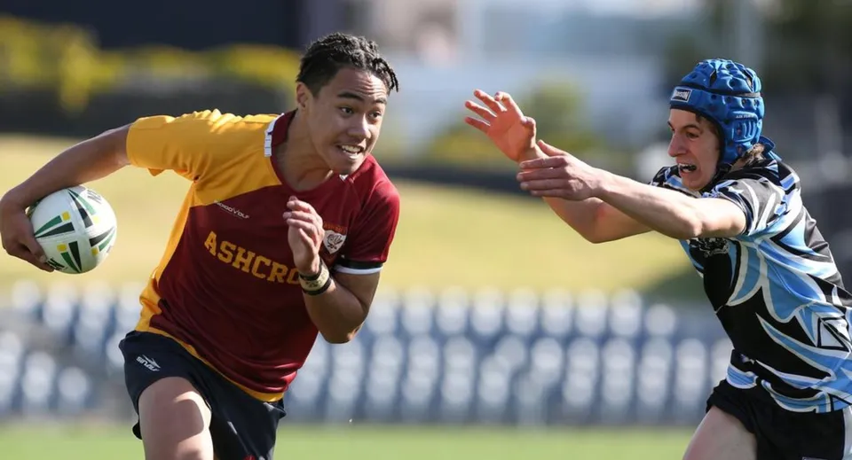 Due giocatori di rugby durante una partita sul campo sportivo della St. Felix School, in cui un giocatore con la maglia rossa cerca di sfuggire al placcaggio dell'avversario.