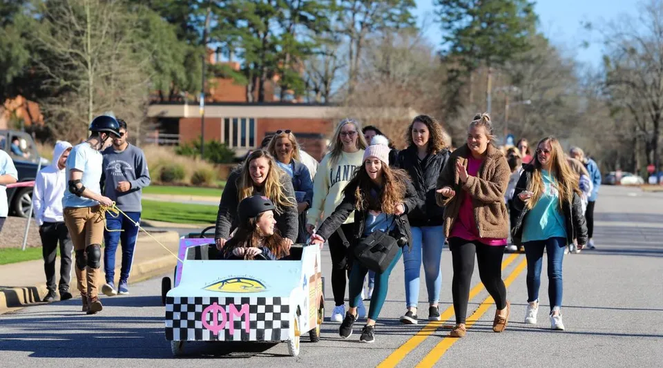 Un gruppo di giovani cammina insieme su un viale pavimentato nel campus della Lander University.