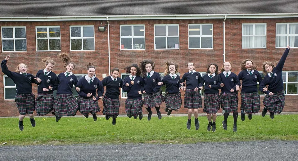 Un gruppo di studenti e studentesse della Presentation Secondary School Kilkenny è davanti a un edificio in mattoni.