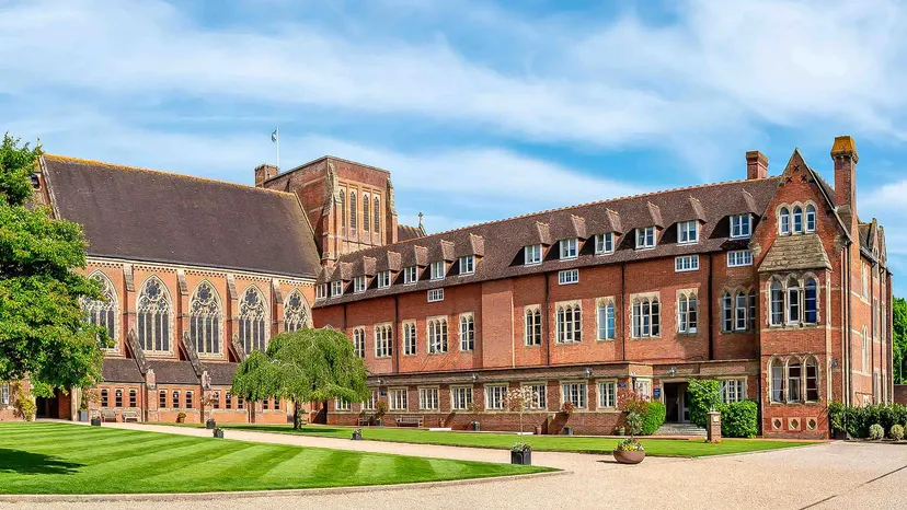 L'edificio storico in mattoni con raffinati dettagli architettonici nel campus dell'Ardingly College è circondato da prati curati e alberi verdi.
