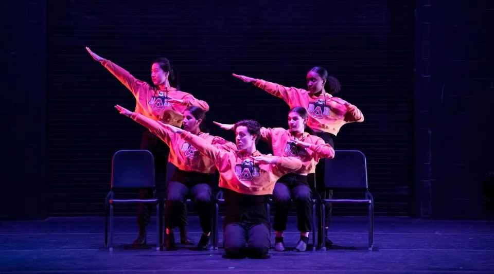 Un gruppo di studenti della Williston Northampton School si esibisce in uno spettacolo di danza su un palco scuro, con costumi colorati.