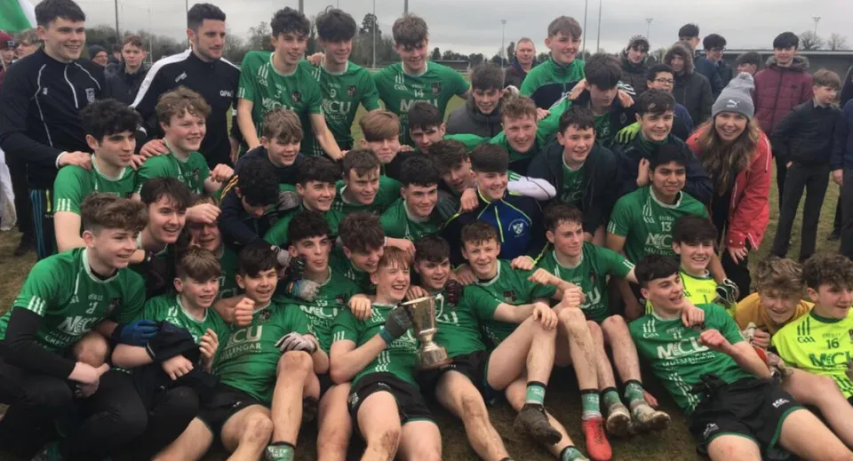 Un grande gruppo di giovani calciatrici e calciatori in maglia verde in posa sul campo da calcio del Coláiste Mhuire Mullingar.