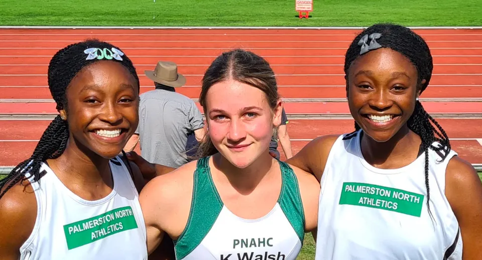 Tre studentesse in divisa da Athletics stanno sulla pista da corsa del St. Peter's College e sorridono insieme.