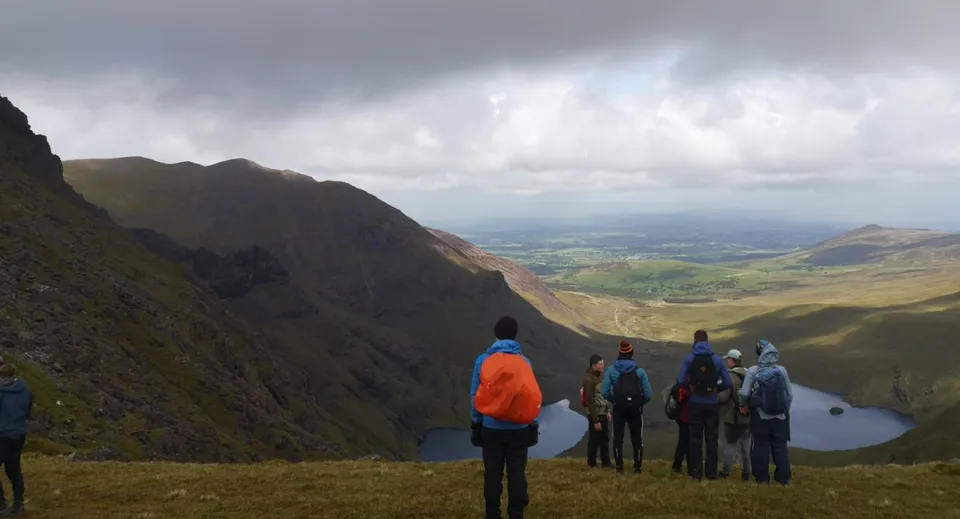 Un gruppo di escursionisti si trova su una roccia con una vista panoramica sulla valle montuosa nel campus del Marist College.