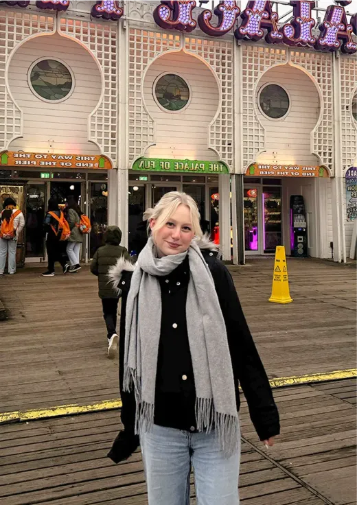 Ann-Kathrin mit grauem Schal vor dem Pier „Palace of Fun“ in England
