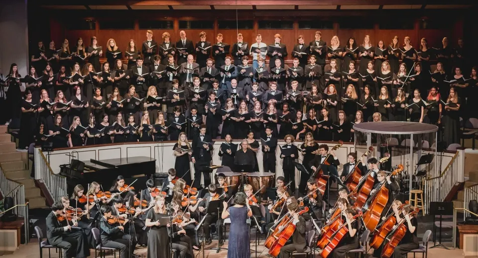 Il coro e l'orchestra del London South Collegiate Institute si esibiscono insieme su un palco.