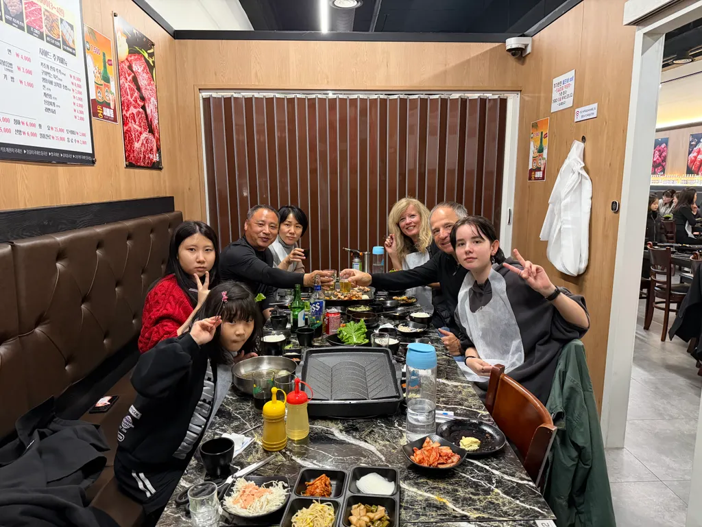 Gruppo a tavola in un ristorante di barbecue coreano fa il segno della pace