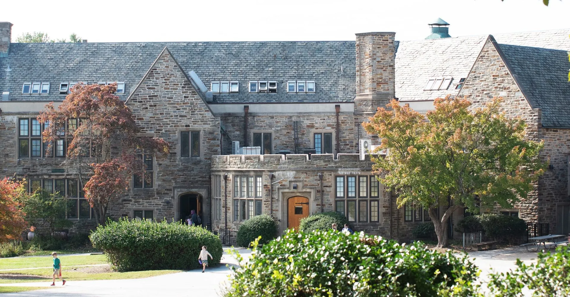 L'edificio in pietra della Friends School of Baltimore circondato da alberi e cespugli nel campus.