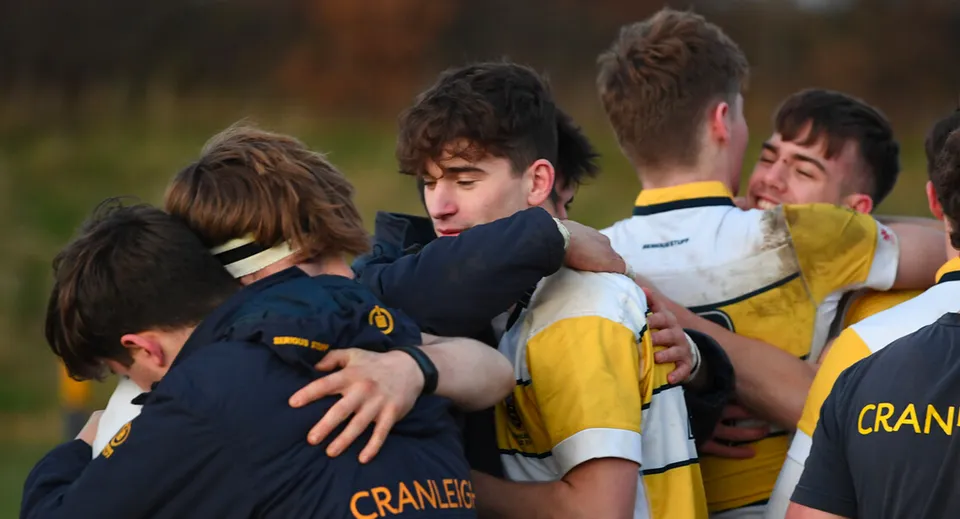 Un gruppo di studenti della Cranleigh School festeggia insieme sul prato in divisa sportiva.