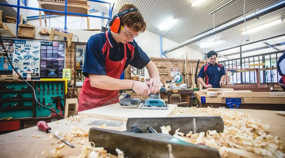 Uno studente o una studentessa della Warwick Senior High School lavora con un utensile elettrico a un progetto in legno in laboratorio.