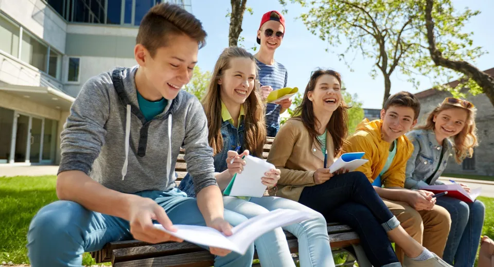 Un gruppo di studenti è seduto su una panchina e chiacchiera nel campus del Provo City School District.