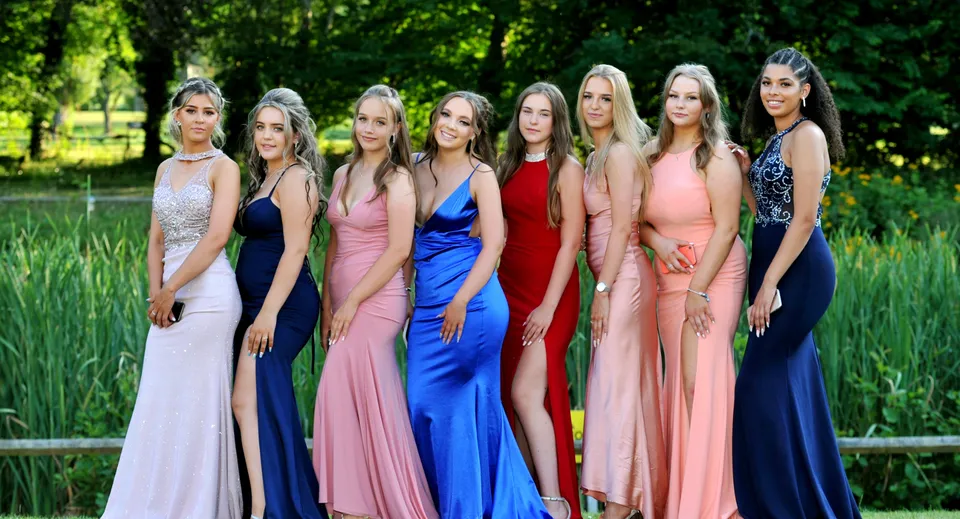 Un gruppo di studentesse di Embley in abiti colorati si trova in un'area verde all'aperto.
