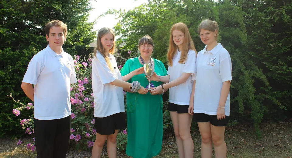 Un gruppo di cinque studenti e studentesse si trova in un'area verde all'aperto nel campus del Baxter College.