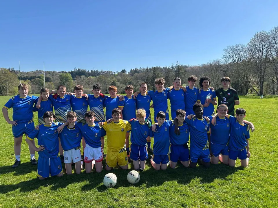 Un gruppo di giovani calciatori del McEgan College si trova su un campo in erba con alberi sullo sfondo.