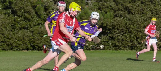 Jugadores con casco disputando un partido de hurling en un campo de hierba