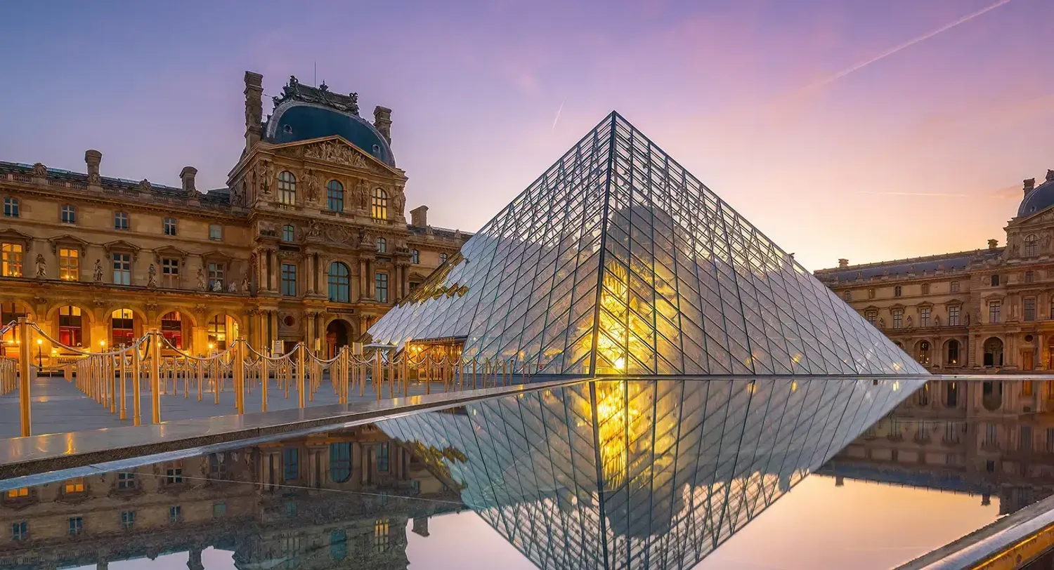 La piramide di vetro del Louvre illuminata al tramonto con il riflesso nell'acqua, Parigi