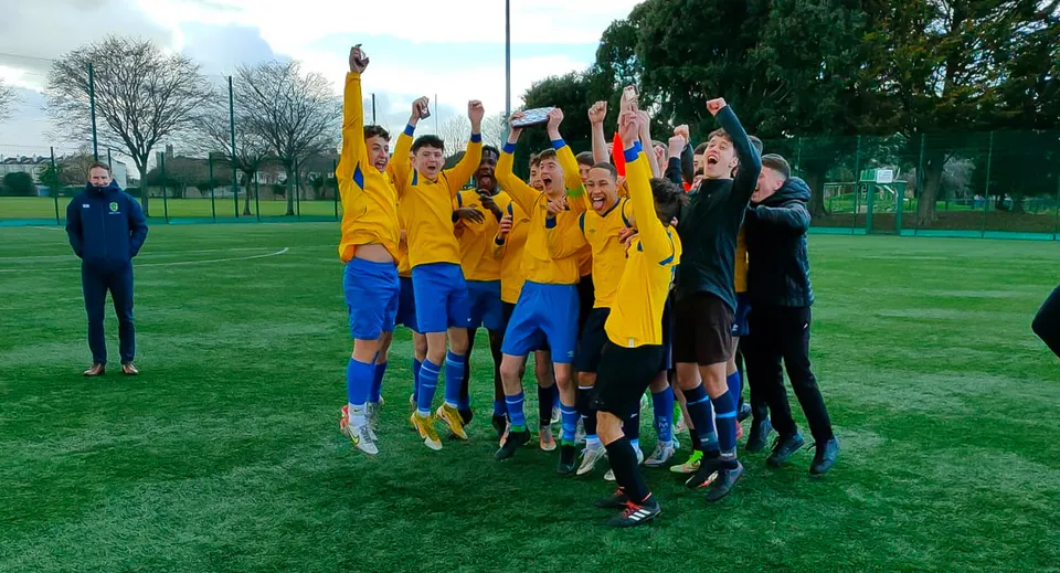 Un gruppo di giovani calciatori festeggia insieme sul campo sportivo del Marian College.