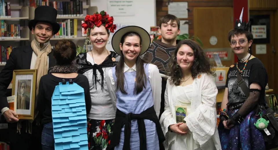 Un gruppo di studenti si trova nella biblioteca del Rosny College davanti agli scaffali dei libri.