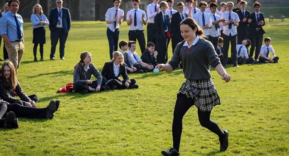 Studenti del Dover College eseguono un esercizio di danza e movimento di gruppo su un prato.