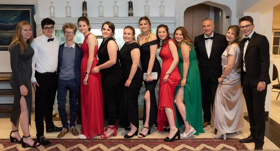 Un gruppo di persone vestite in modo elegante posa insieme in una sala formale al Glenalmond College.