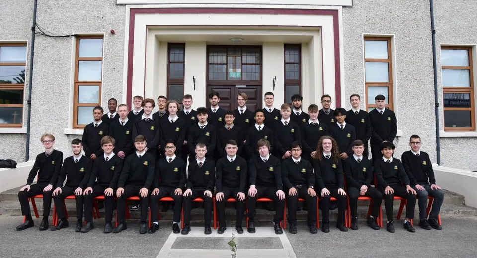 Un gruppo di studenti del De la Salle College Churchtown in divisa scolastica formale davanti a un magnifico edificio.