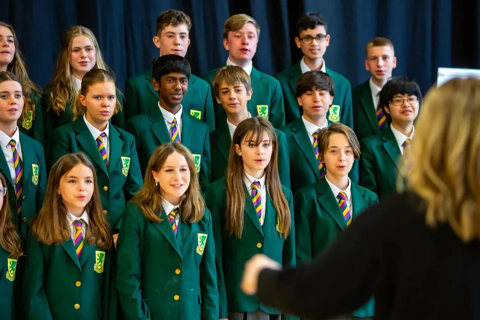 Gli studenti della Sandford Park School cantano in un coro scolastico indossando divise verdi.