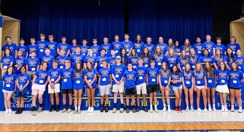 Un gruppo di studenti della Bethlehem High School si trova insieme su un palco davanti a un sipario blu.