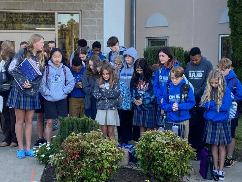 Un gruppo di studenti della Teays Valley Christian School è all'aperto davanti a un edificio scolastico con piante sullo sfondo.