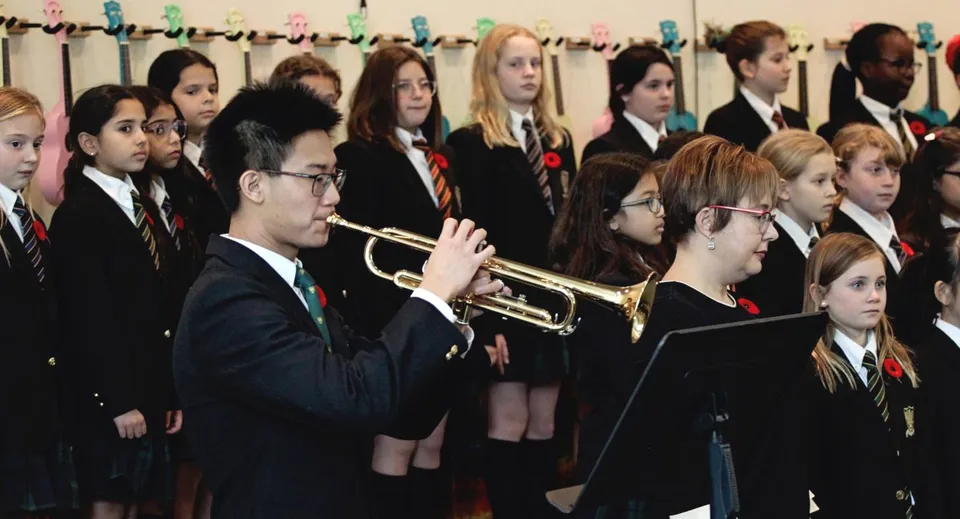 Un gruppo di studenti della St. John’s-Ravenscourt School è insieme in divisa scolastica con strumenti musicali in mano.