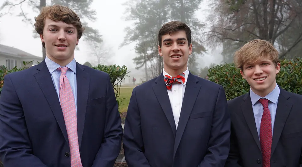 Tre studenti della St. Christopher’s School sono insieme all'aperto davanti ad alberi e aree verdi.