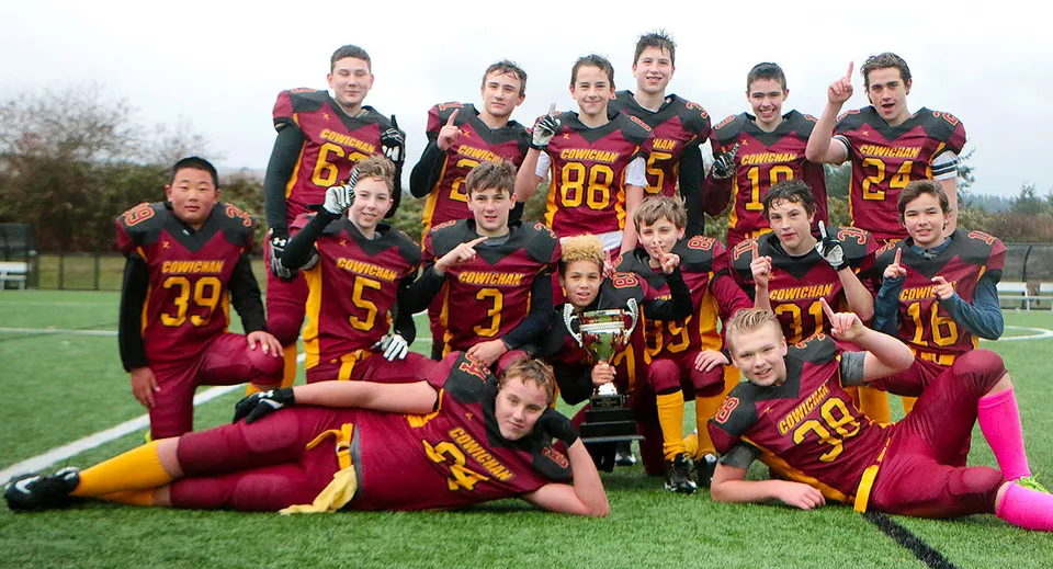 Un gruppo di studenti della Lake Cowichan Secondary School posa in abbigliamento sportivo su un campo in erba.