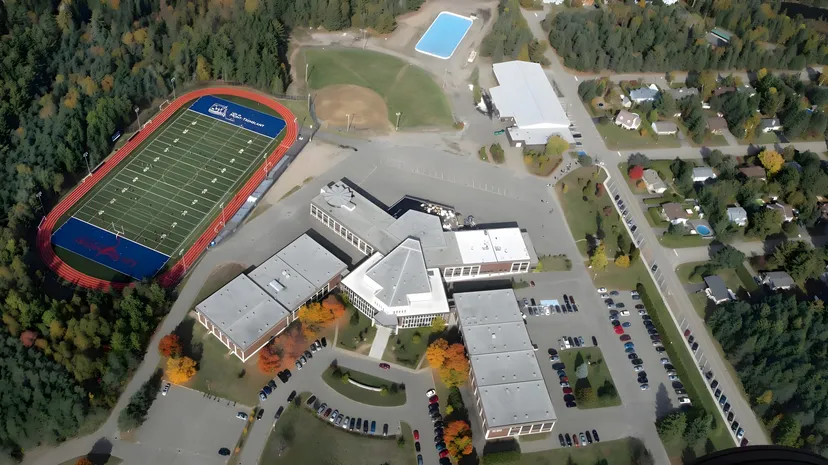 Vista aerea del campus della École Polyvalente Secondaire Curé-Mercure con edifici scolastici, campo sportivo e parcheggi.