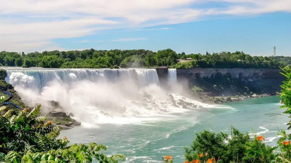 Una cascata scorre su una parete rocciosa, circondata da una verde vegetazione, visibile vicino alla École Secondaire Hugh McRoberts Secondary School.