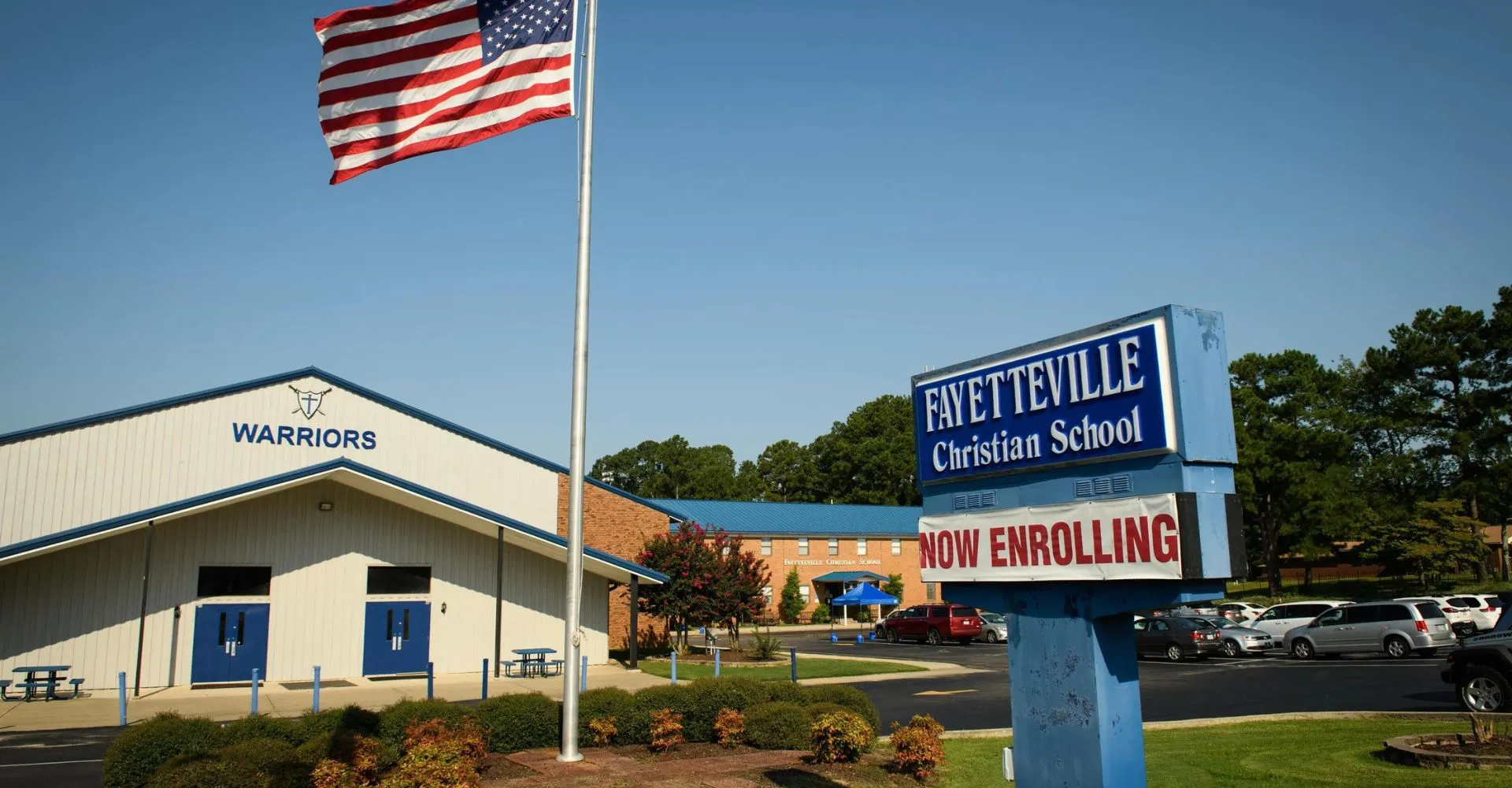 Nel campus della Fayetteville Christian School si vedono una bandiera americana e un cartello relativo all'iscrizione degli studenti.