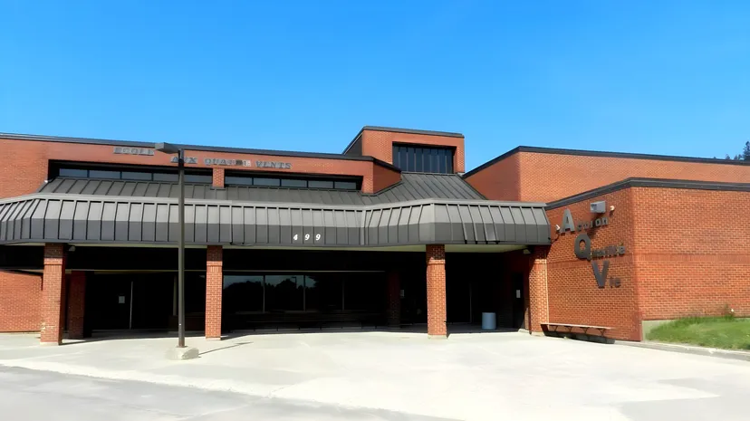 L'edificio moderno in mattoni con grandi vetrate nel campus della École Aux quatre vents sotto un cielo limpido.