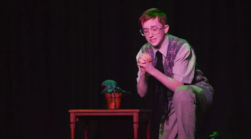 Uno studente del Stewart’s Melville College è inginocchiato sul palco accanto a una pianta durante una recita teatrale.